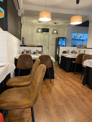 Mesas con sillas marrones en el comedor de Chispa y Leña
