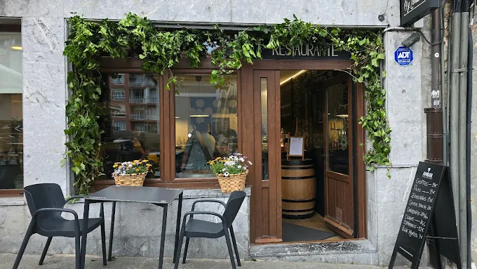 Fachada de Chispa y Leña con hiedra y terraza en la calle